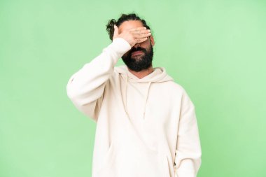 Young man with beard over isolated chroma key background covering eyes by hands. Do not want to see something