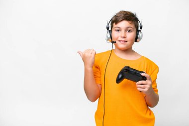 Beyaz arka planda video oyunu kontrolörüyle oynayan küçük beyaz bir çocuk bir ürünü sunmak için kenarı işaret ediyor.