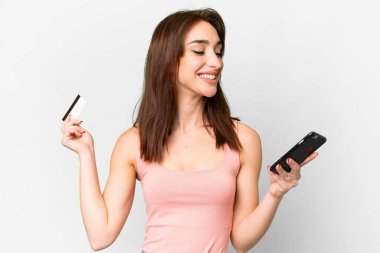 Young caucasian woman over isolated white background buying with the mobile with a credit card