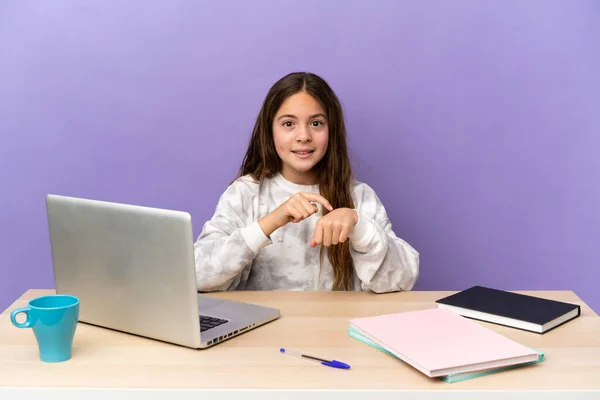 Little student girl in a workplace with a laptop isolated on purple background making the gesture of being late