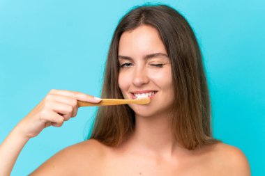 Mavi arka planda diş fırçasıyla izole edilmiş beyaz bir kadın.