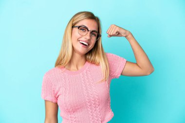 Blonde Uruguayan girl isolated on blue background doing strong gesture