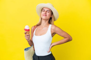 Blonde Uruguayan girl in summertime holding ice cream isolated on yellow background suffering from backache for having made an effort