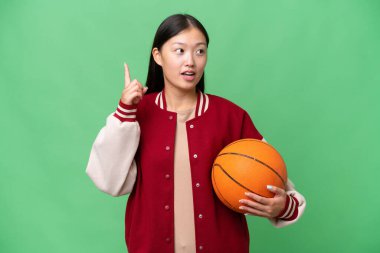Young basketball player asian woman over isolated background thinking an idea pointing the finger up