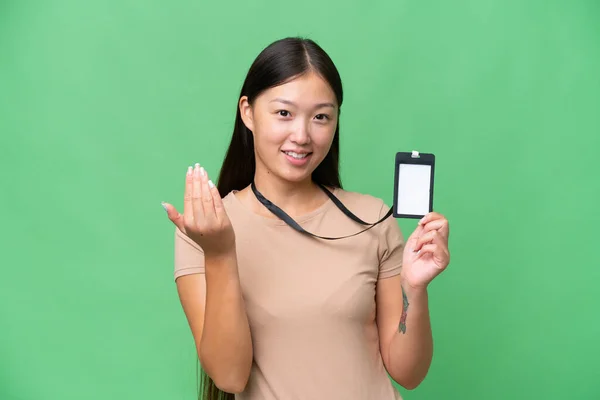 Young Asian woman with ID card over isolated background inviting to come with hand. Happy that you came
