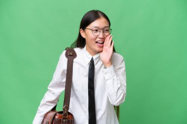 Young Asian business woman over isolated background shouting with mouth wide open to the lateral
