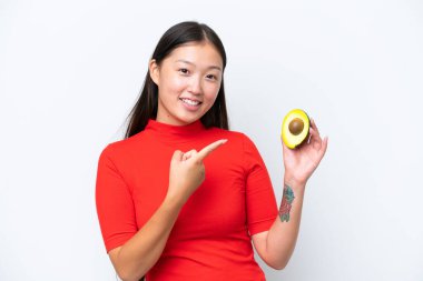 Young Asian woman holding an avocado isolated on white background and pointing it