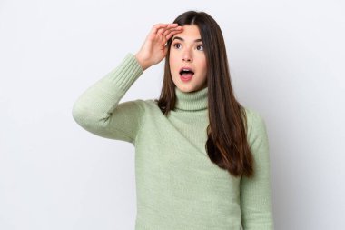 Genç Brezilyalı bir kadın beyaz arka planda izole edilmiş ve sürpriz bir ifadeyle yan tarafa bakıyor.