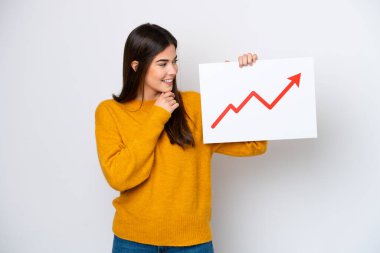 Young Brazilian woman isolated on white background holding a sign with a growing statistics arrow symbol and thinking