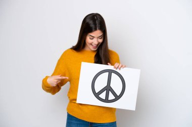 Genç Brezilyalı bir kadın beyaz arka planda izole edilmiş. Elinde barış sembolü olan bir pankart var.
