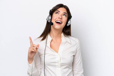 Beyaz arka planda izole edilmiş bir kulaklıkla çalışan beyaz pazarlamacı kadın yukarı bakıyor ve şaşırıyor.