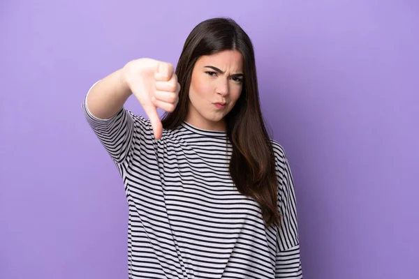 Young Brazilian woman isolated on purple background showing thumb down with negative expression