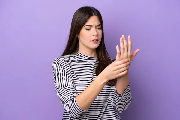 Young Brazilian woman isolated on purple background suffering from pain in hands