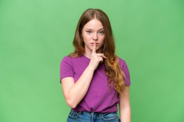 Genç ve güzel bir kadın, izole edilmiş arka planda sessizce hareket ettiğini gösteriyor. Parmağını ağzına sok.