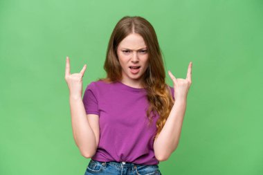 Young pretty woman over isolated background making horn gesture