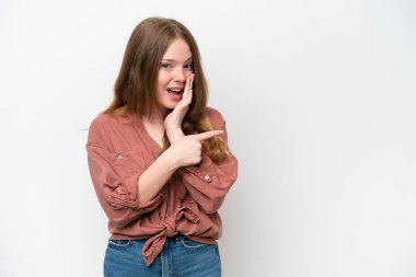 Young pretty woman isolated on white background pointing to the side to present a product and whispering something