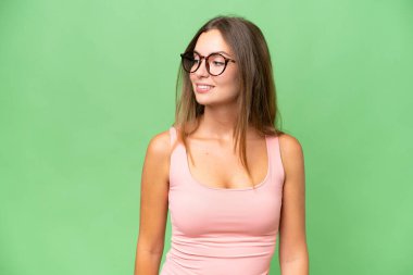 Genç ve güzel bir kadın, izole edilmiş arka planda yan tarafa bakıyor ve gülümsüyor.