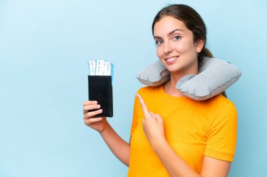 Young beautiful woman with Inflatable travel Pillow isolated on blue background pointing back