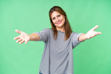 Middle age woman over isolated background presenting and inviting to come with hand