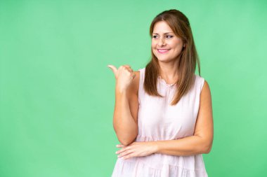 Middle age woman over isolated background pointing to the side to present a product