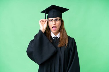 Middle age university graduate woman over isolated background with glasses and surprised
