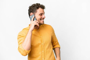 İzole edilmiş beyaz arka planı olan Brezilyalı bir adam cep telefonuyla sohbet ediyor.