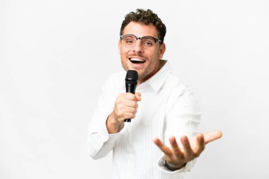 Brezilyalı bir adam izole edilmiş beyaz arka planda bir mikrofon tutuyor.