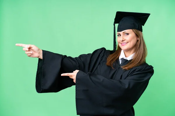 Middle age university graduate woman over isolated background pointing finger to the side and presenting a product