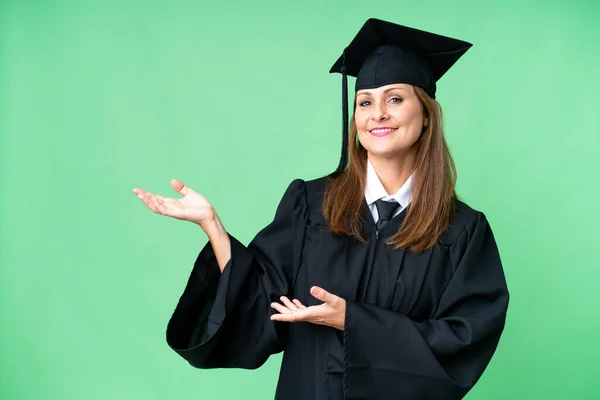 Middle age university graduate woman over isolated background extending hands to the side for inviting to come
