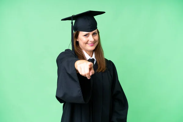 Middle age university graduate woman over isolated background points finger at you with a confident expression