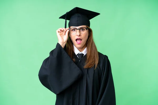 Middle age university graduate woman over isolated background with glasses and surprised