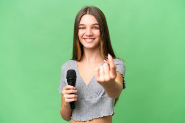 Genç şarkıcı kız izole bir arka planda mikrofonu eline aldı.