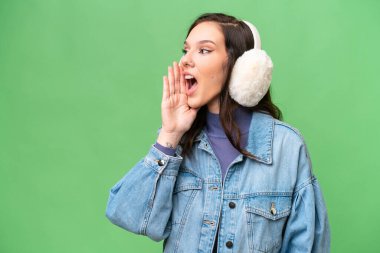 İzole edilmiş arka planda kışlık manşet takan beyaz bir kadın ağzı sonuna kadar açık bağırıyor.