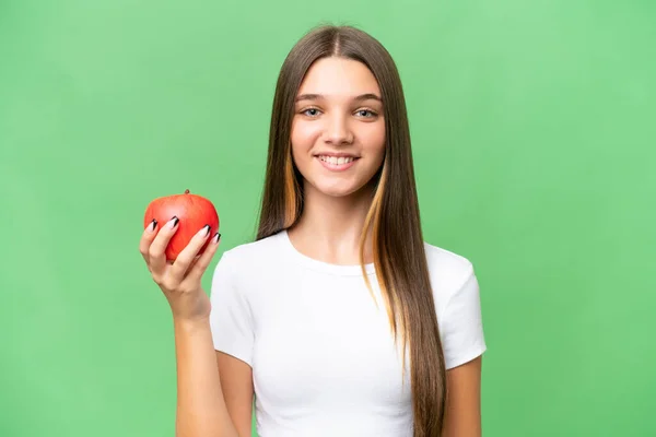 Teenager caucasian girl holding an apple over isolated background smiling a lot