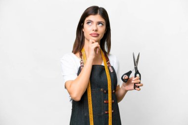 Seamstress woman over isolated white background having doubts and thinking