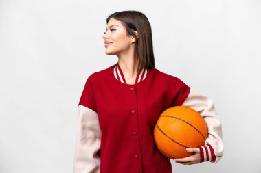 Young Russian woman playing basketball over isolated white background looking side