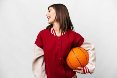 Young Russian woman playing basketball over isolated white background laughing in lateral position
