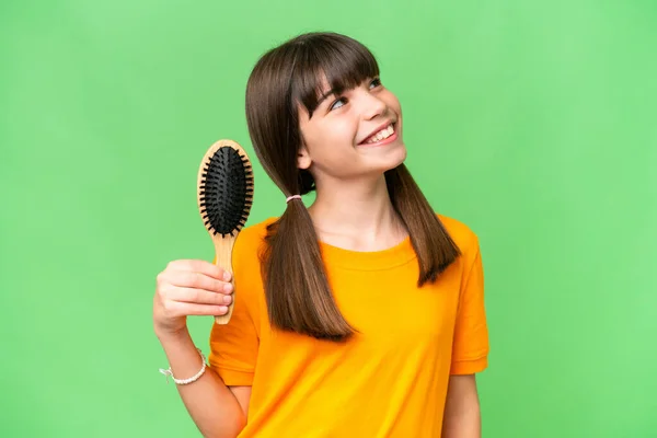 Little caucasian girl with hair comb over isolated background looking up while smiling