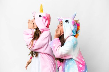 Friends girls with unicorn pajamas over isolated white background shouting with mouth wide open to the lateral