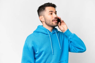 İzole edilmiş beyaz geçmişi olan yakışıklı beyaz bir adam cep telefonuyla sohbet ediyor.