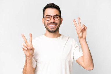 İzole edilmiş beyaz arka planı olan yakışıklı beyaz bir adam zafer işareti gösteriyor.