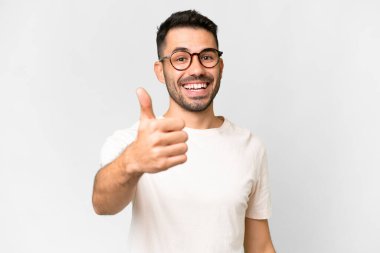 İzole edilmiş beyaz arka planı olan yakışıklı beyaz bir adam. Başparmakları havada çünkü iyi bir şey oldu.