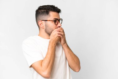 İzole edilmiş beyaz arka planı olan yakışıklı beyaz bir adam ağzını kapatıyor ve yan tarafa bakıyor.