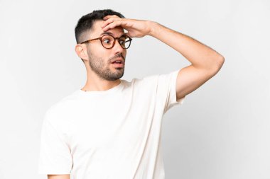 Beyaz arka plan üzerinde genç, yakışıklı beyaz bir adam. Yan tarafa bakarken sürpriz jest yapıyor.