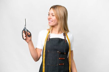 Young blonde Seamstress woman over isolated white background looking side