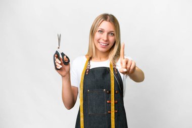 Young blonde Seamstress woman over isolated white background showing and lifting a finger