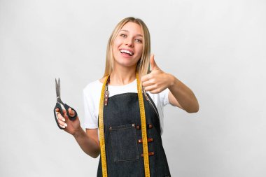 Young blonde Seamstress woman over isolated white background with thumbs up because something good has happened
