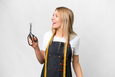 Young blonde Seamstress woman over isolated white background laughing in lateral position