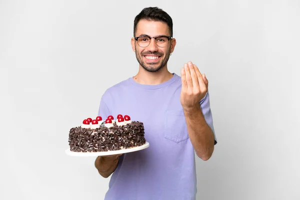 白地に隔離された誕生日ケーキを持っている若い白人男性が手を携えて来るように誘います 来てくれて嬉しい — ストック写真