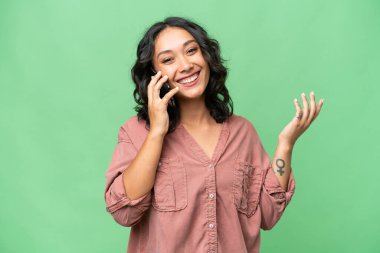 Arjantinli genç bir kadın izole edilmiş bir arka planda cep telefonuyla sohbet ediyor.